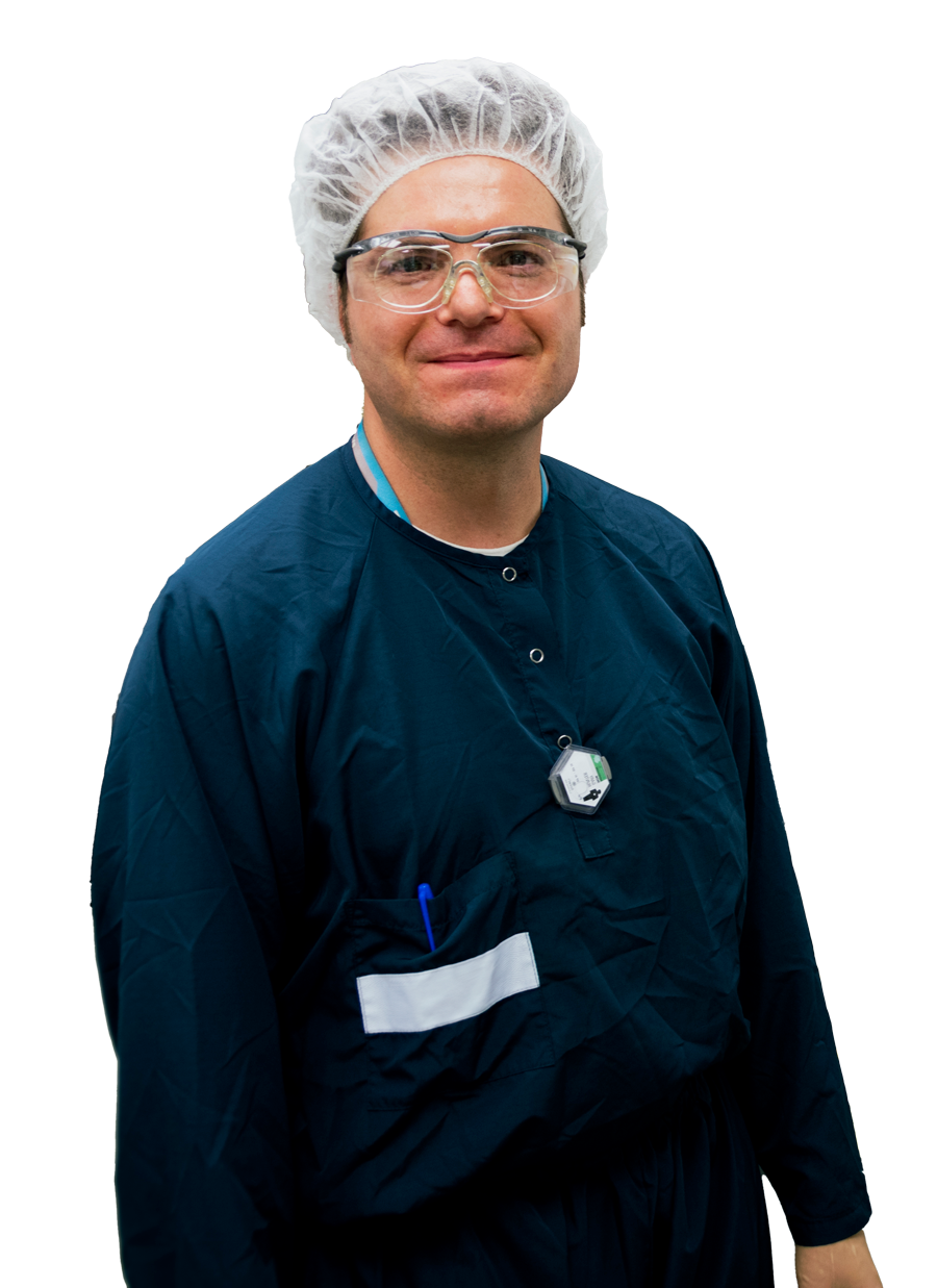 Male lab technician in blue uniform smiles at camera.