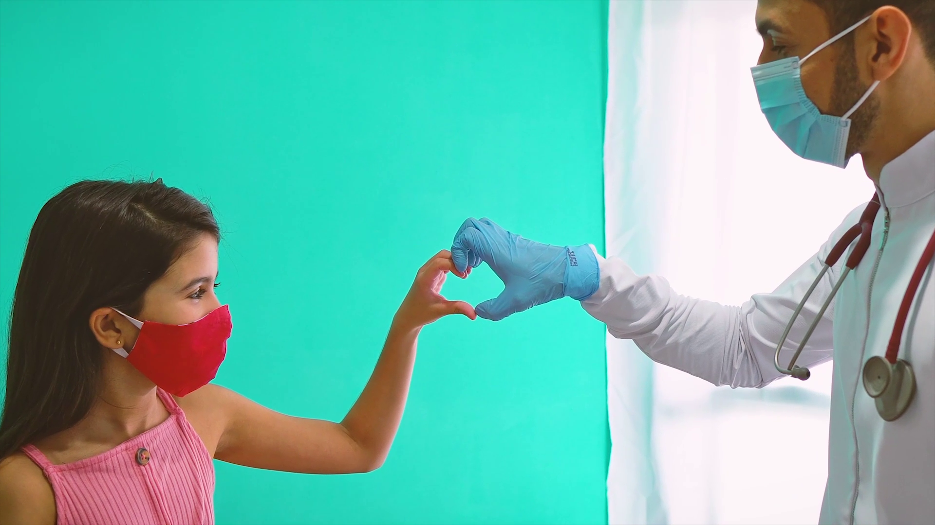 A girl and a Dr tough hands making the heart symbol.